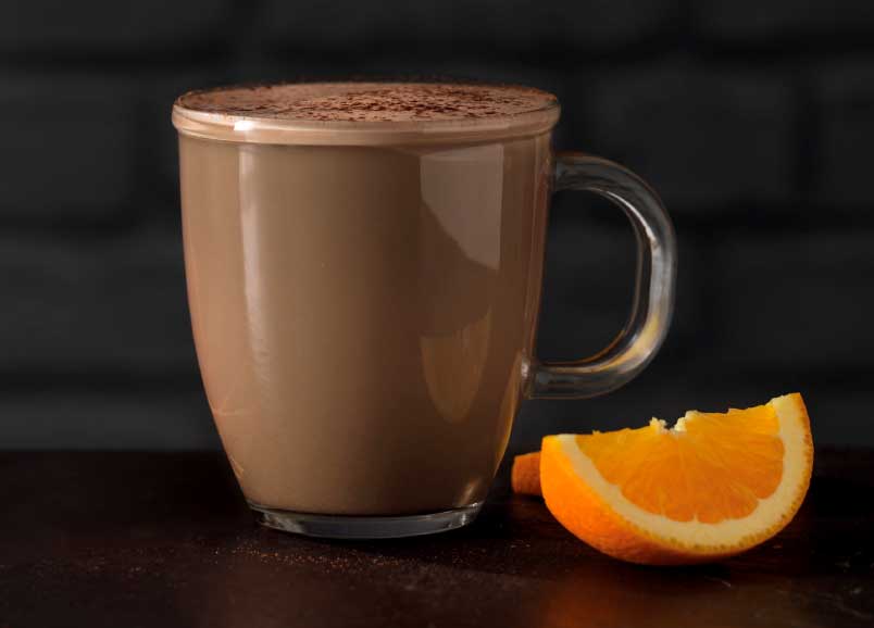 Orange chocolate latte with a slice of orange next it