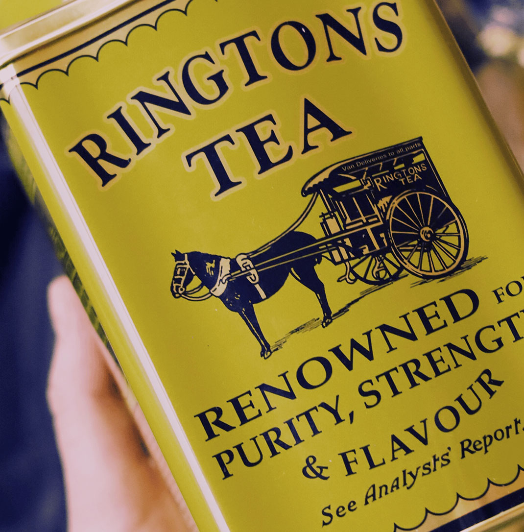 A close up of a green metal Ringtons tea caddy