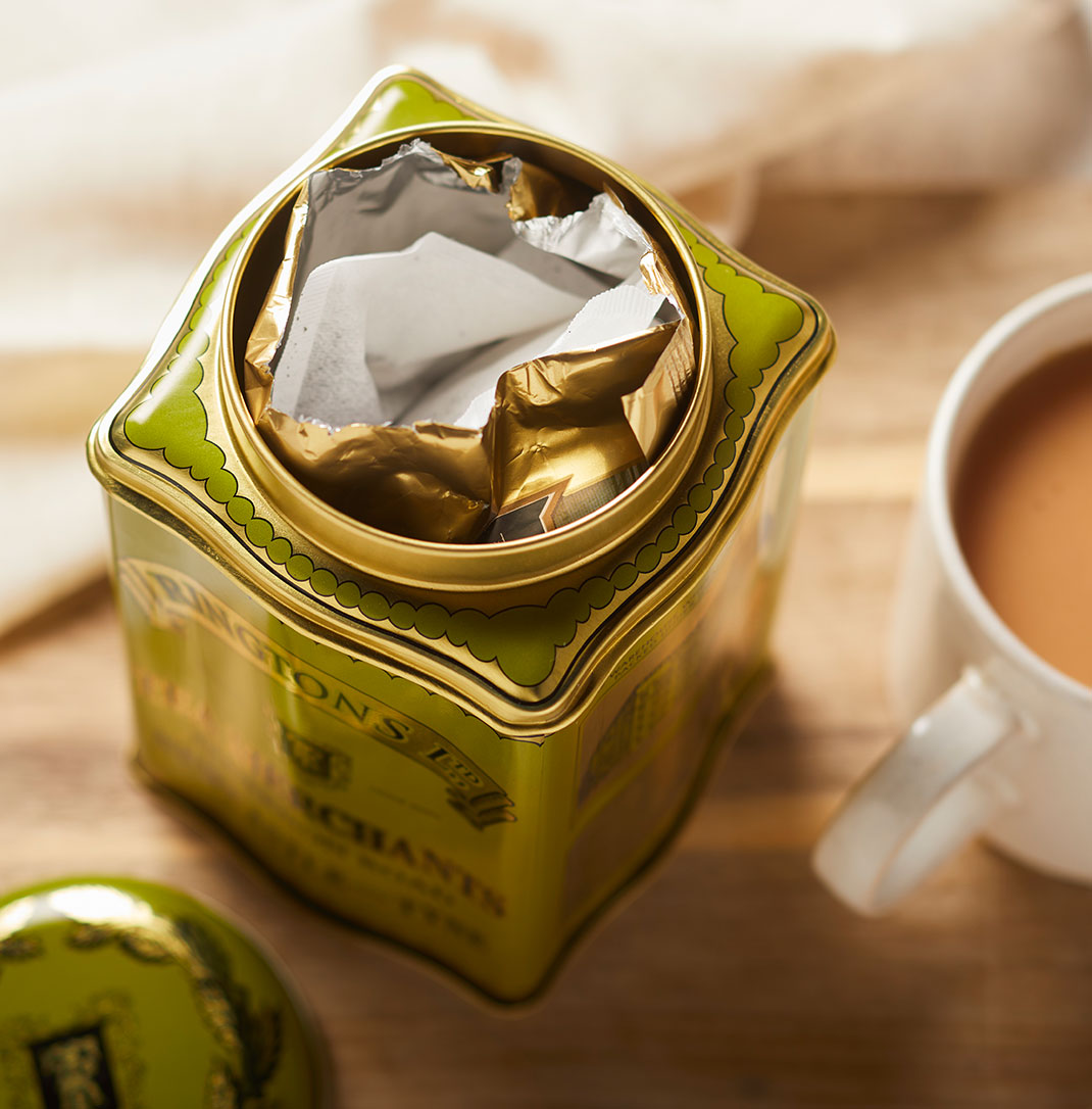 A green metal Ringtons tea caddy with teabags inside