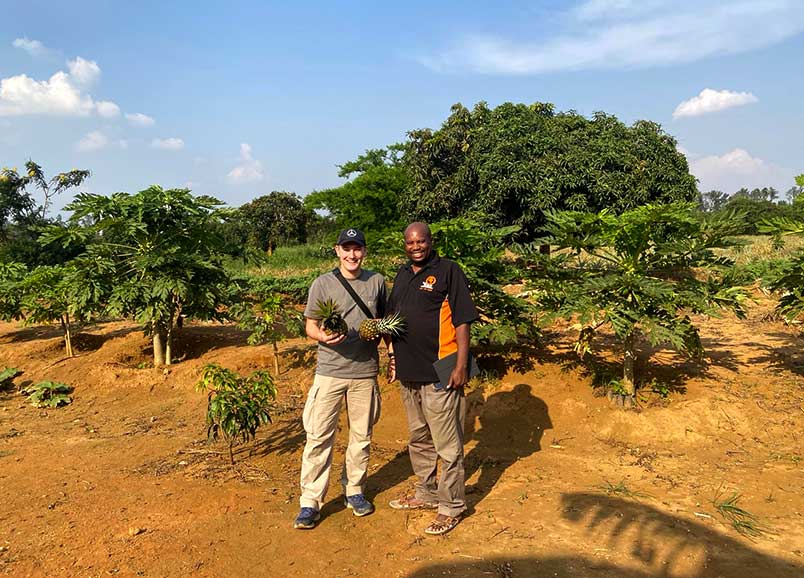 Origin trip photo to Africa with Chris holding two pineapples
